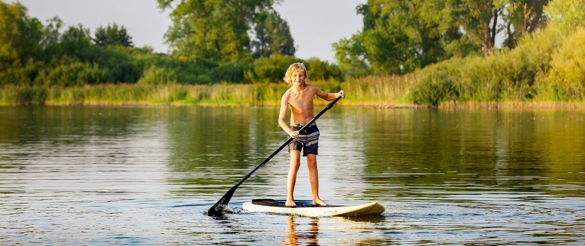 Junge beim Stand-up-Paddeln auf einem See in Mecklenburg