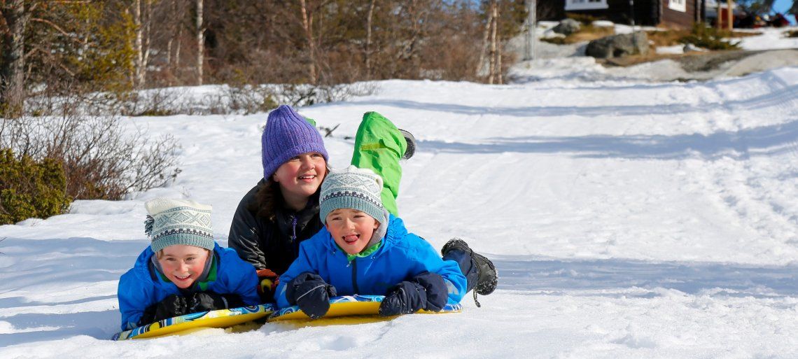 Kinder beim Rodeln im Schnee in Norwegen