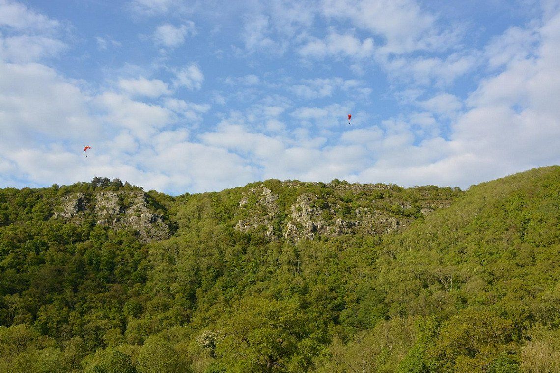 Wald, Felsen und Paraglider in der Normannischen Schweiz