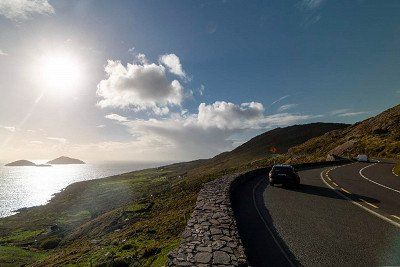 Pkw und Linksverkehr auf der Kuestenstrasse Derrynane in Irland