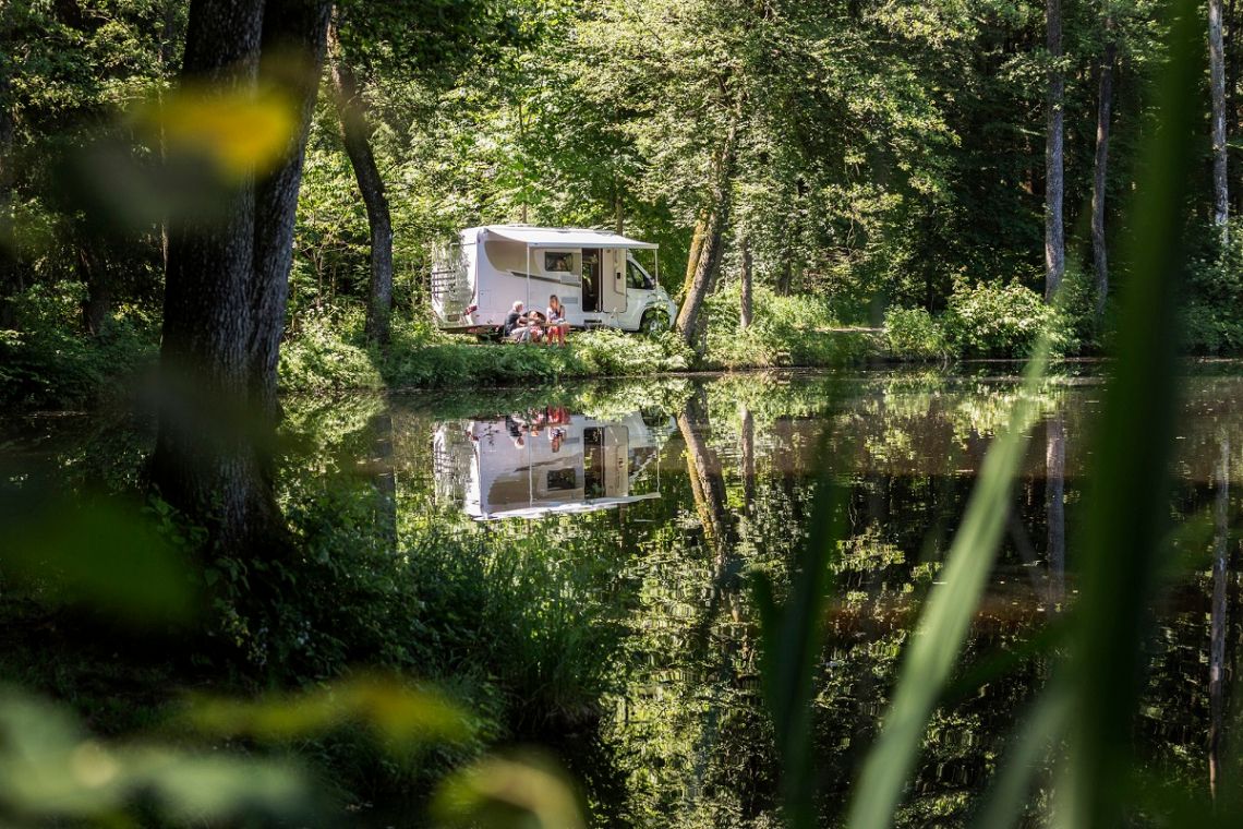Carado Wohnmobil unter Bäumen am See