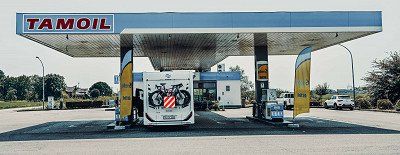 Carado motorhome with rear bicycle rack and warning sign at gas station in Italy