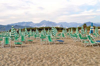 Sandstrand und Sonnenstuehle vor Bergpanorama