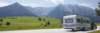 LMC Caravan-Gespann auf Strasse in Oesterreich vor Bergkulisse 