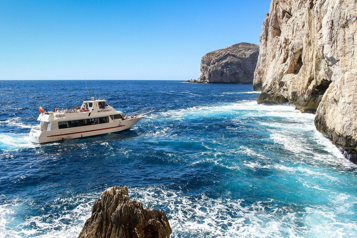Touristenboot vor dem Eingang der Neptungrotte auf Sardinien 