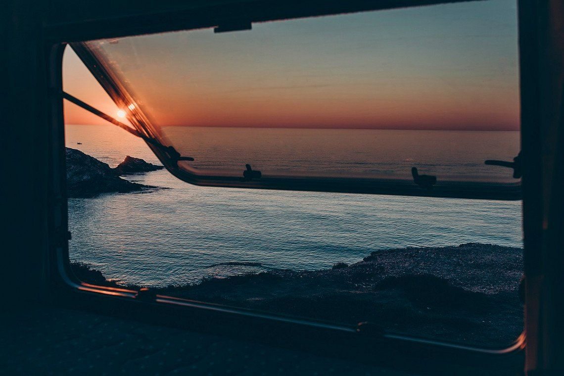 Zonsondergang aan zee op Sardinië gezien vanuit het raam van de camper