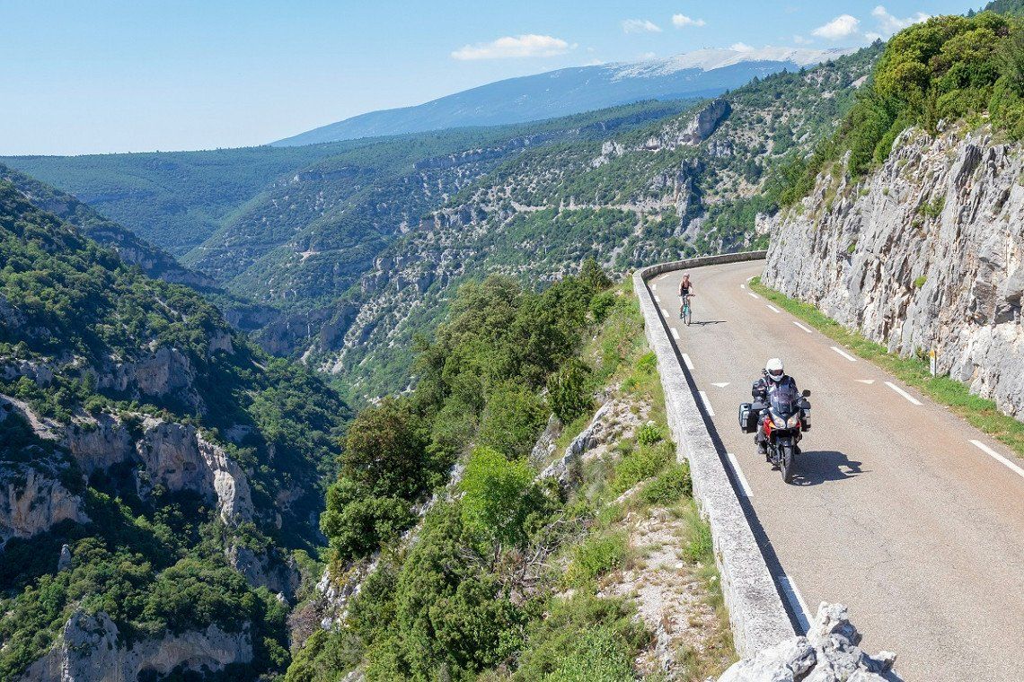 Motorradfahrer und Radfahrer auf der Strasse durch die Nesque-Schlucht im Vaucluse