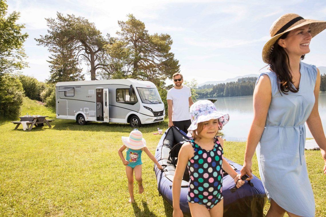 A Dethleffs Trend motorhome by a lake with a family