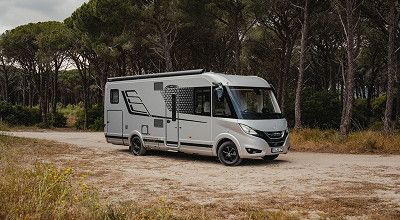 integriertes Hymer Wohnmobil B-ML BlackLine von seitlich vorne mit Pinien im Hintergrund 