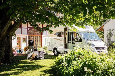 Mann belädt Carado Wohnmobil vor dem Haus 