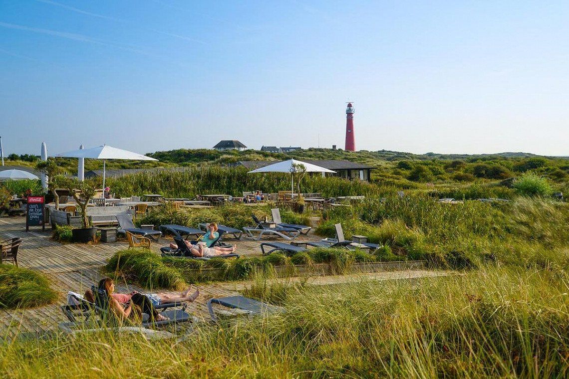 Sonnenliegen, Duenen und Leuchtturm auf der Insel  Schiermonnikoog