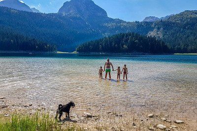 Vater mit Kindern und Hund im See in Montenegro