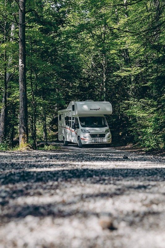 A Sunlight coachbuilt motorhome on a gravel road in the forest