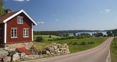 Sommeridylle in Schweden mit rotem Holzhaus, See und Wald