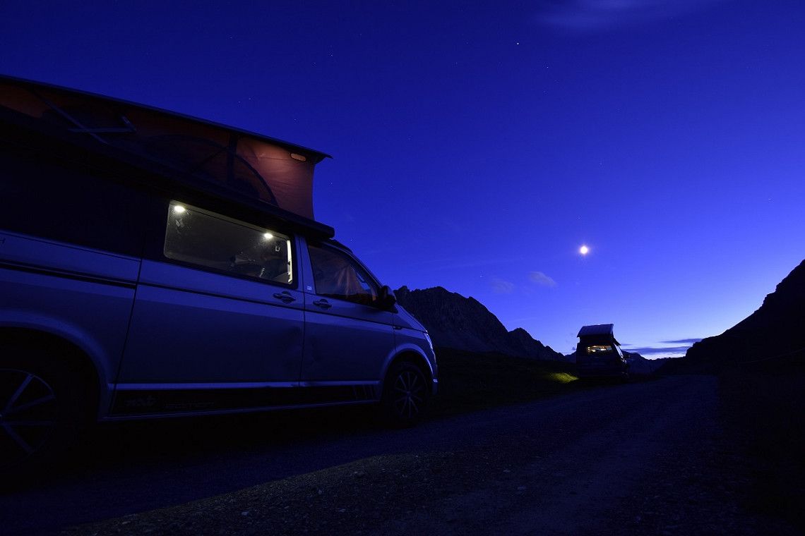 Two urban campervans with pop-up roofs in the mountains at night