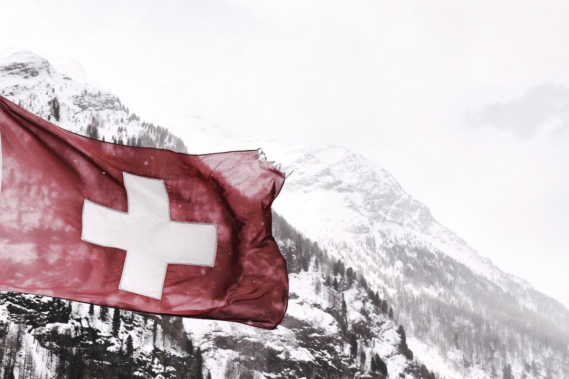 Schweizer Flagge vor winterlicher Berglandschaft
