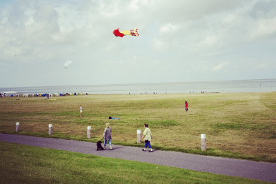 Menschen beim Drachensteigen lassen auf Strandwiese