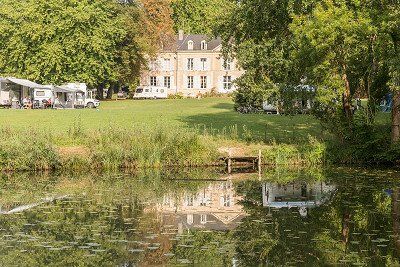 View of the meadow and manor house at the Château de Chanteloup campsite