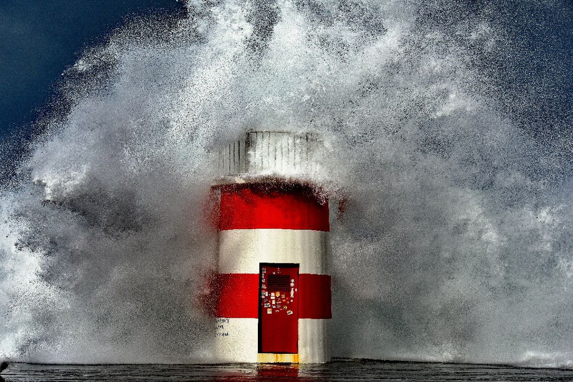 Riesenwelle brechend am Leuchtturm im Hafen Porto de Abrigo 