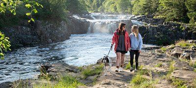 Couple walking with a dog alongside Low Force Waterfall,Bowlees, Durham Dales