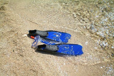 Flossen und Schnorchel im Wasser am Strand