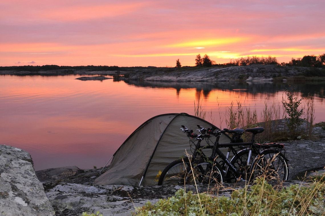 Zelt und Fahrraeder bei Sonnenuntergang auf den Aland-Inseln